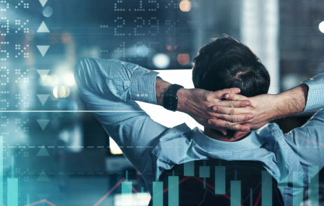 Photo d’une personne assise de dos et se relaxant en se tenant la tête devant un écran d’ordinateur