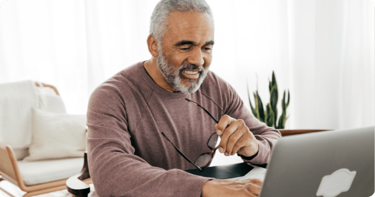 Photo d’un homme souriant devant son ordinateur portable dans son bureau éclairé