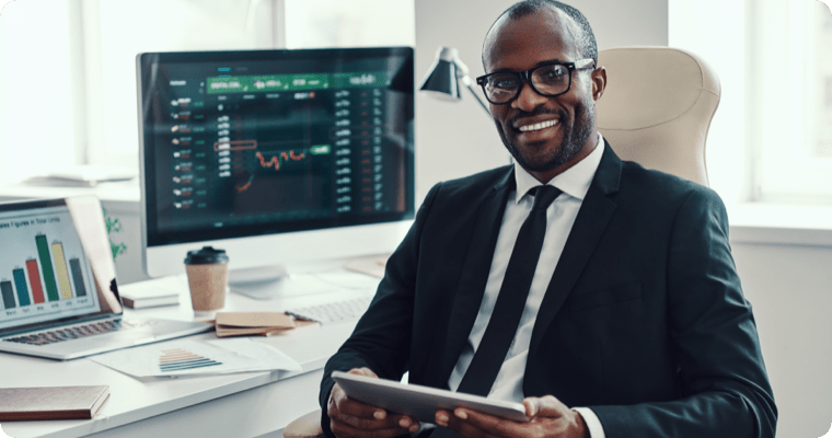 Photo d’un homme souriant qui tient une tablette dans son bureau