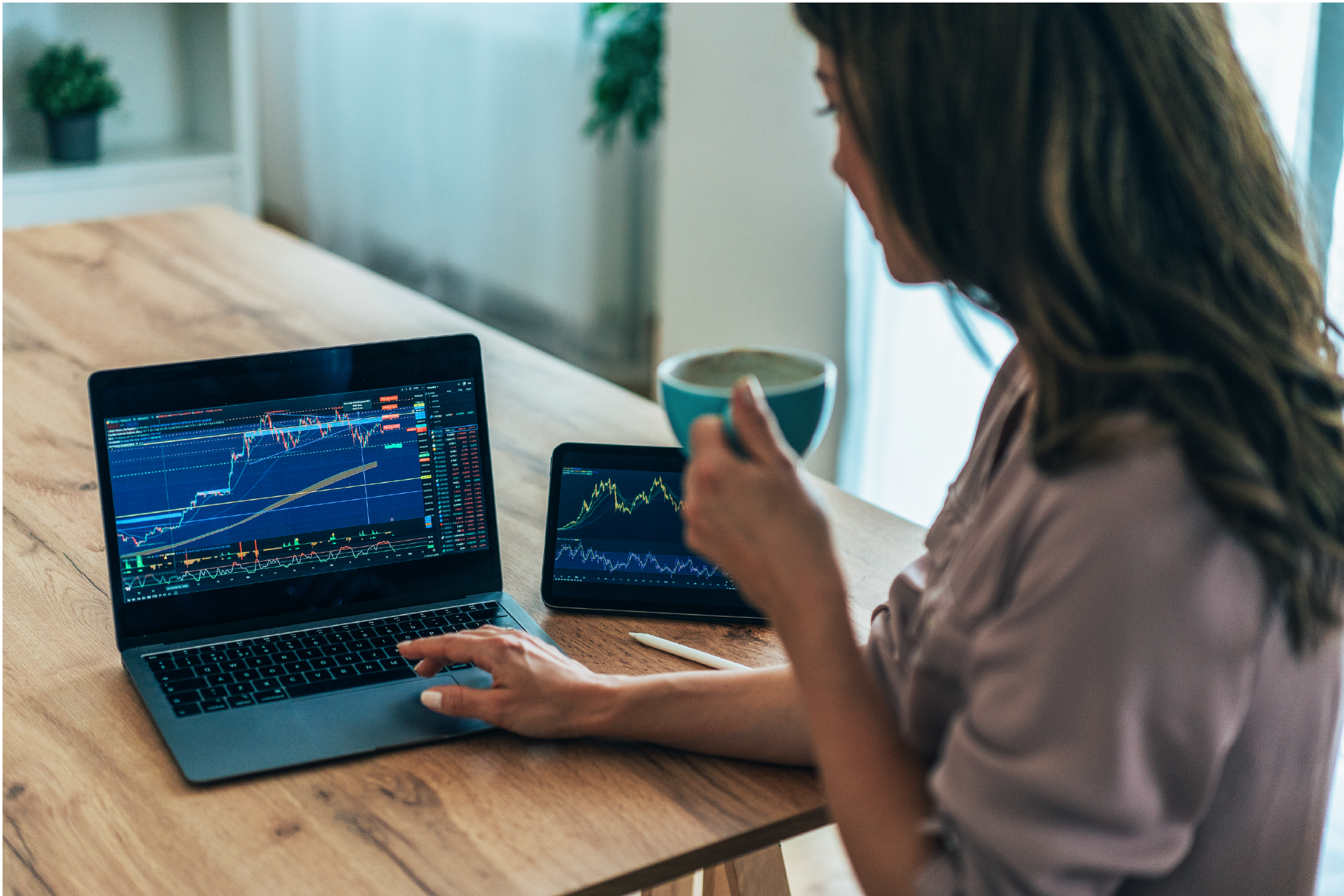 Femme analysant des graphiques financiers sur un ordinateur portable et une tablette