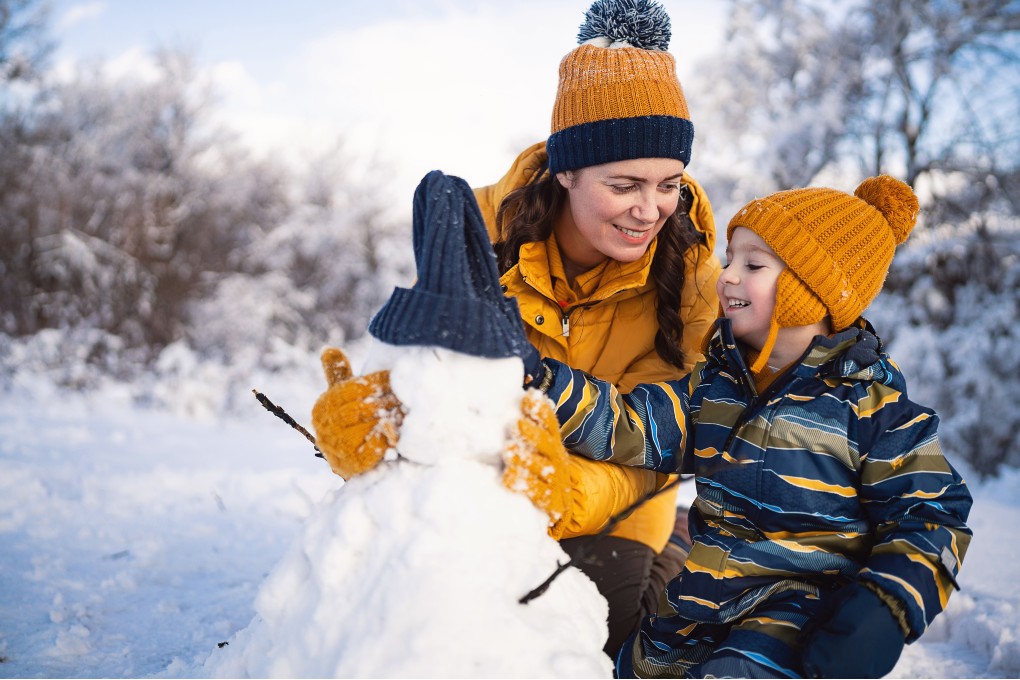 Une mère et son fils qui construisent un bonhomme de neige pendant le mois de janvier. 