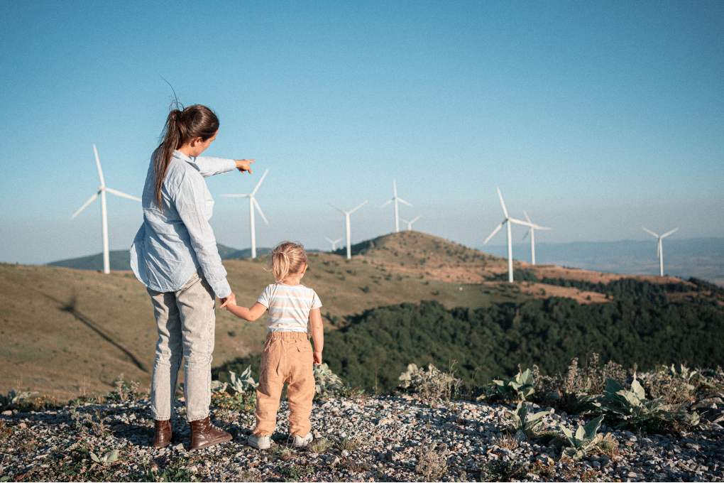 Une image d’une femme et sa jeune fille qui regardent un paysage avec des éoliennes.