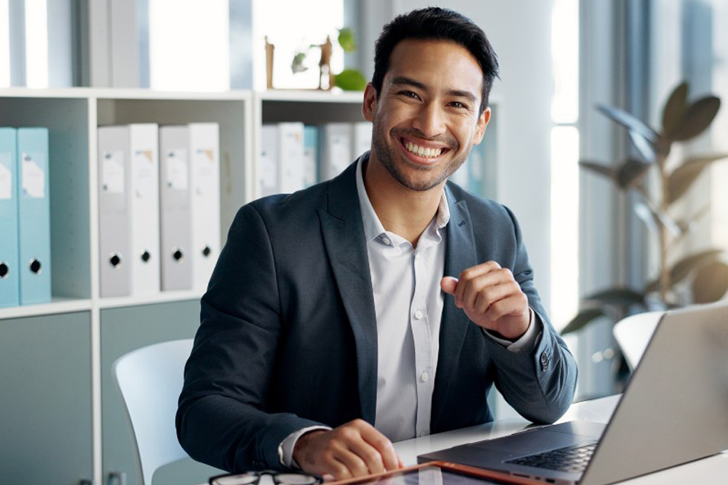 Un homme souriant qui investit dans les fonds indiciels et les FNB grâce à son ordinateur.