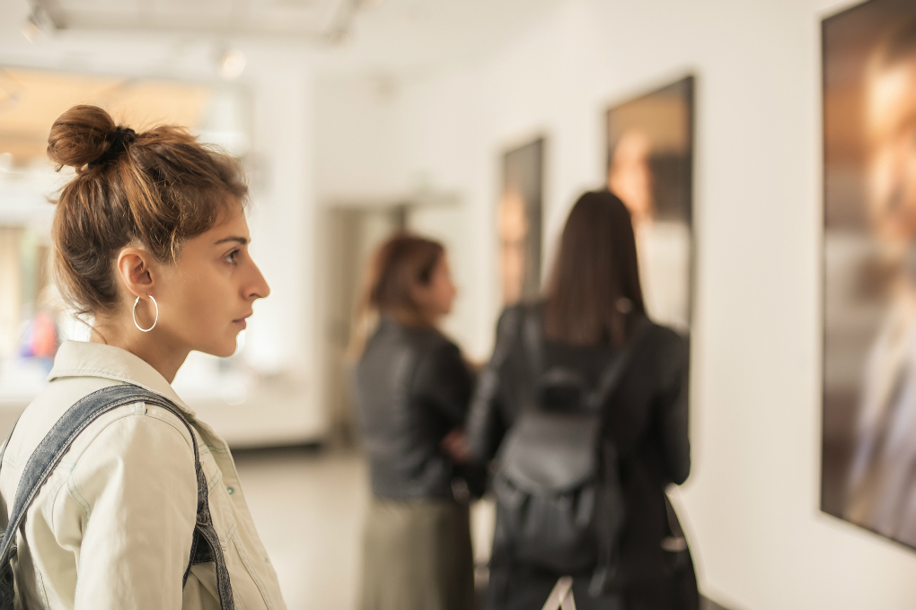 Investir dans l'art Photo d’une femme contemplant les tableaux d’une galerie d’art.