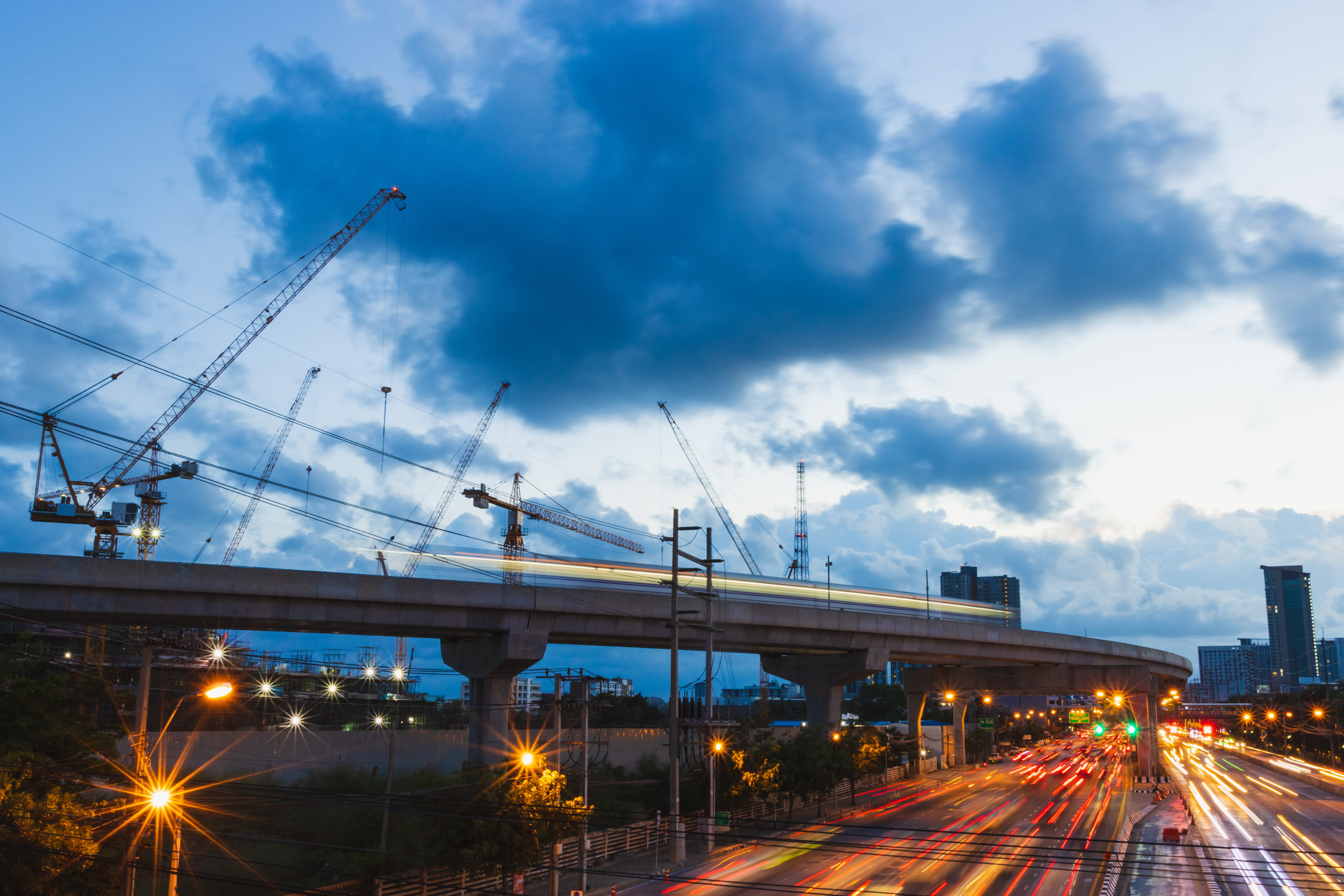 Pont surélevé, grues et voitures sous ciel nuageux